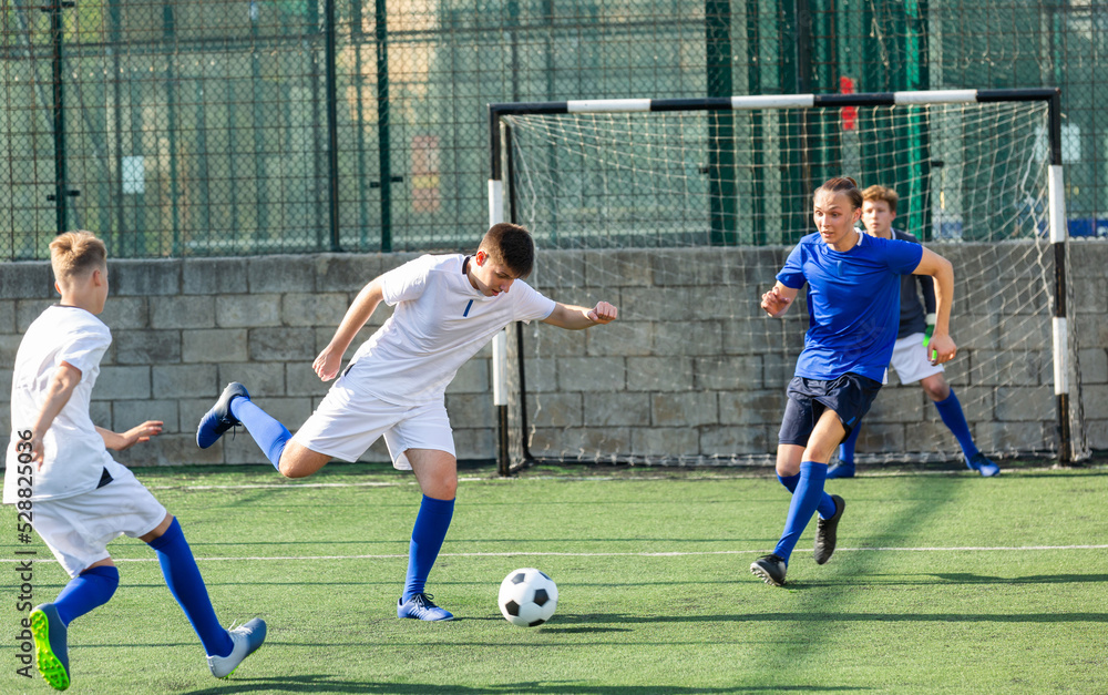 Obraz premium Football soccer players with ball. Footballers kicking football match on the pitch. Young teen soccer game