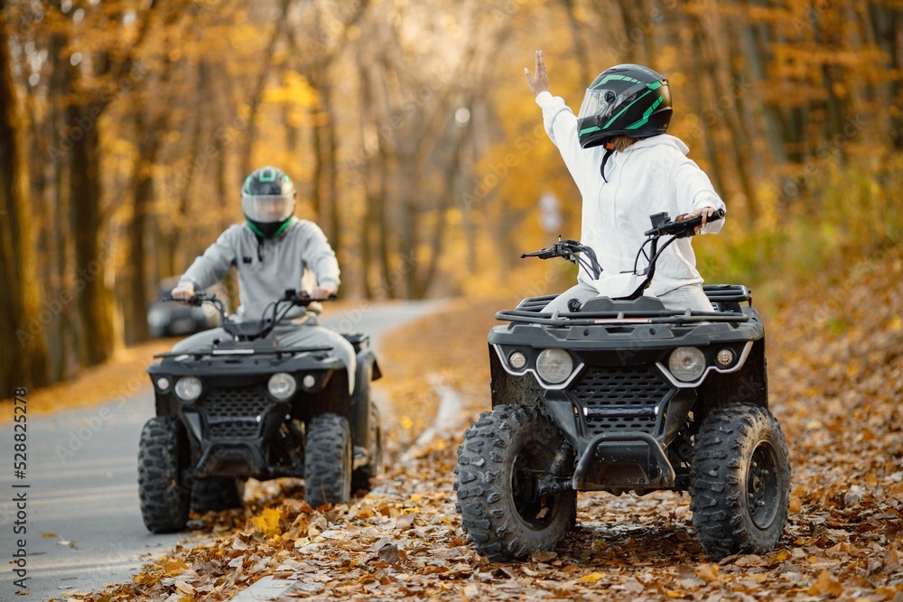 Fototapeta premium Man and woman driving quad bike in autumn forest