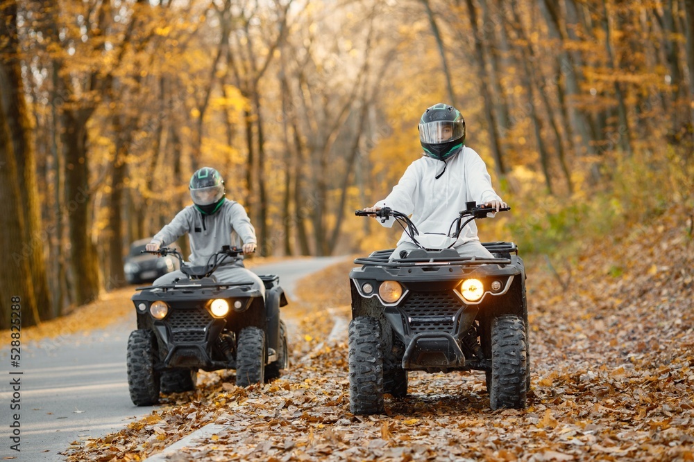 Fototapeta premium Man and woman driving quad bike in autumn forest