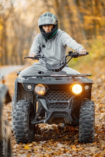 Young man driving quad bike in autumn forest
