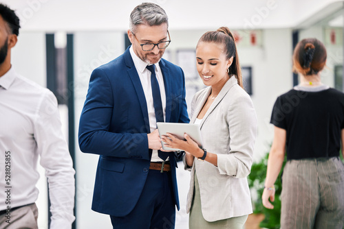 Business people with a digital tablet while talking, planning and brainstorming together at work. Ceo, leader or boss and young female worker talking after a meeting in a corporate startup office