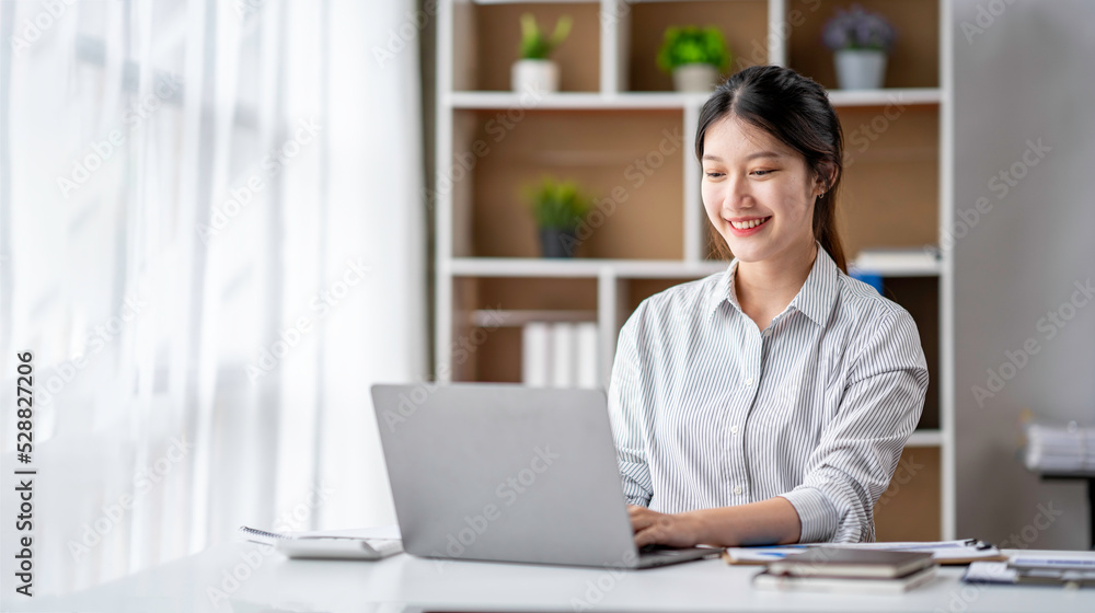 Young woman working on a laptop in the office. Asian businesswoman sitting at her workplace in the office. Beautiful Freelancer Woman working online at her home. Young woman working on a laptop in the office. Asian businesswoman sitting at her workplace in the office. Beautiful Freelancer Woman working online at her home.