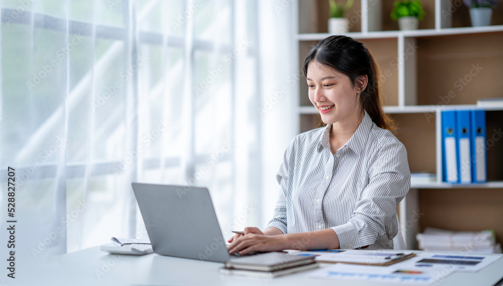 Young woman working on a laptop in the office. Asian businesswoman sitting at her workplace in the office. Beautiful Freelancer Woman working online at her home. Young woman working on a laptop in the office. Asian businesswoman sitting at her workplace in the office. Beautiful Freelancer Woman working online at her home.