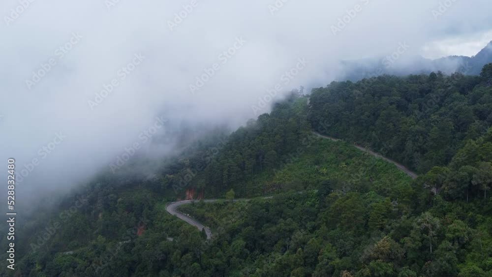 Aerial view of a hilltop road with beautiful green forests in Thailand. Landscape of nature background in motion. Travel and transportation concept Aerial view of a hilltop road with beautiful green forests in Thailand. Landscape of nature background in motion. Travel and transportation concept