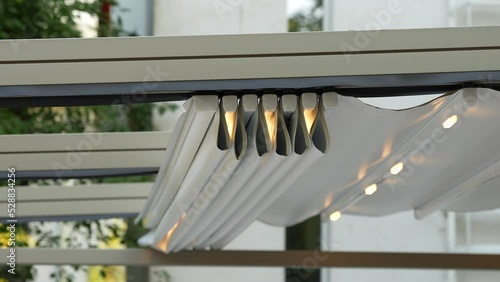 4k video, the move of a retractable awning of roof for protect from sun in garden at home or in terrace at a restaurant. 