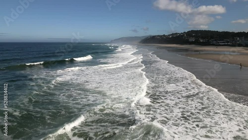 Aerial drone shot over the ocean at the beach during the day.