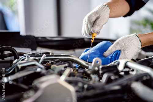 Close up of Automotive mechanic repairman pulling dipstick to checking engine oil level engine in the engine room, check the mileage of the car, oil change, auto maintenance service concept.