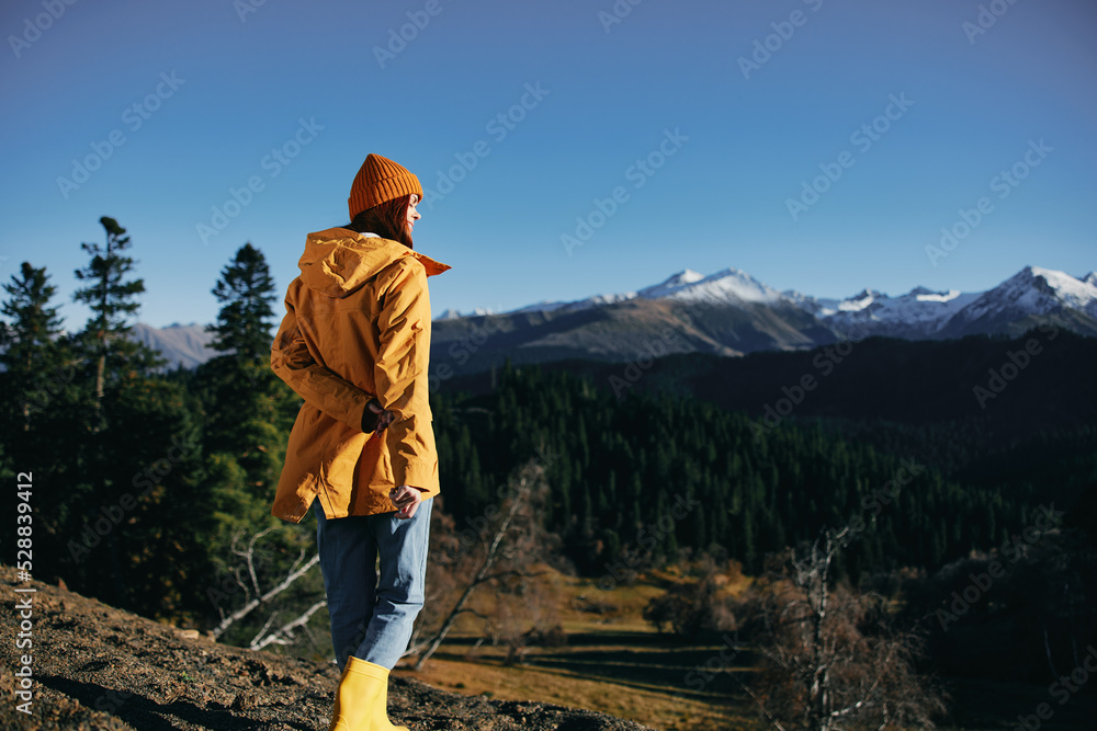 Woman full-length hiker standing frozen on the mountain looking at nature happiness with a view of the mountains in a yellow raincoat travel and hiking in the mountains at sunset freedom Woman full-length hiker standing frozen on the mountain looking at nature happiness with a view of the mountains in a yellow raincoat travel and hiking in the mountains at sunset freedom