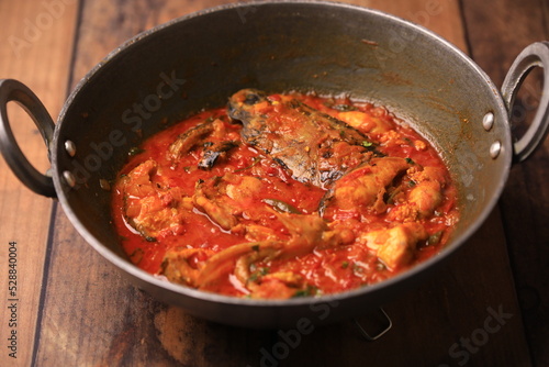 Indian desi style fish curry cooked in a traditional pot closeup with selective focus and blur