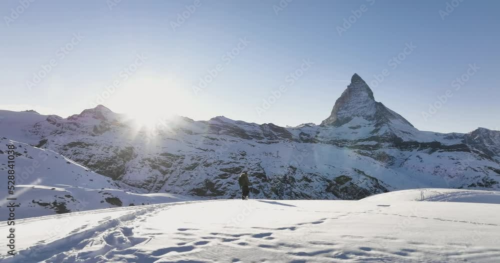 Aerial drone of Young man tourist hiker walking in snow shoes. Successful climber hiking up to mountain top swiss alps, Switzerland. Active travel lifestyle winter outdoor activities. Slow motion. Aerial drone of Young man tourist hiker walking in snow shoes. Successful climber hiking up to mountain top swiss alps, Switzerland. Active travel lifestyle winter outdoor activities. Slow motion.