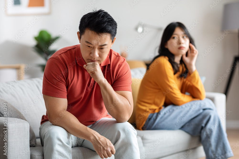 Selective focus on pensive asian man, having fight with wife Selective focus on pensive asian man, having fight with wife