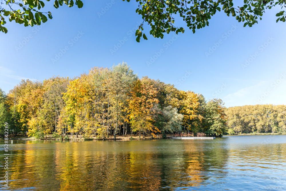 bright autumn trees under clear blue sky are reflected in the water of lake bright autumn trees under clear blue sky are reflected in the water of lake