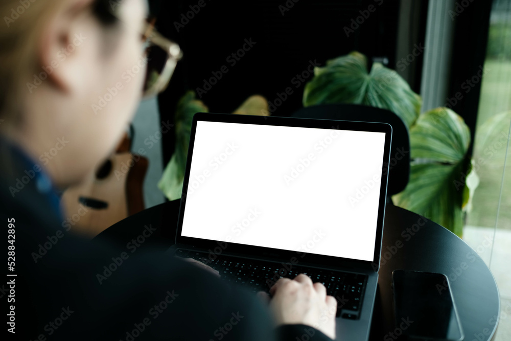 Mockup image of a businesswoman using laptop with blank white desktop screen with coffee cup on wooden table in cafe. Mockup image of a businesswoman using laptop with blank white desktop screen with coffee cup on wooden table in cafe.