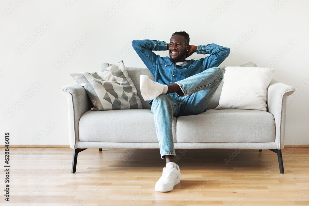 Happy Black Guy Sitting On Sofa Relaxing At Home Happy Black Guy Sitting On Sofa Relaxing At Home