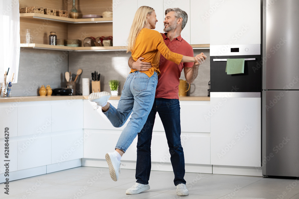 Loving middle aged couple having fun at kitchen, dancing Loving middle aged couple having fun at kitchen, dancing
