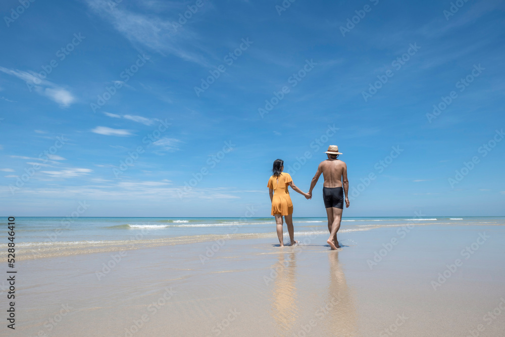 Happy couple in love, playing on the beach at sunny, running and splashing in the waves, travel vacation lifestyle