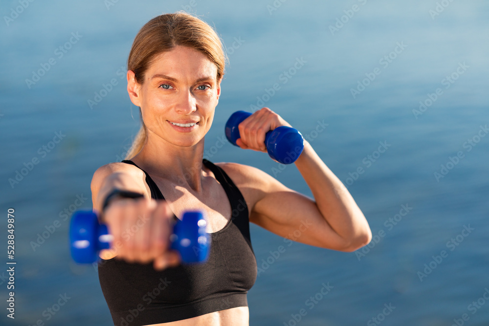 Portrait Of Athletic Middle Aged Woman Training With Dumbbells Outdoors Portrait Of Athletic Middle Aged Woman Training With Dumbbells Outdoors