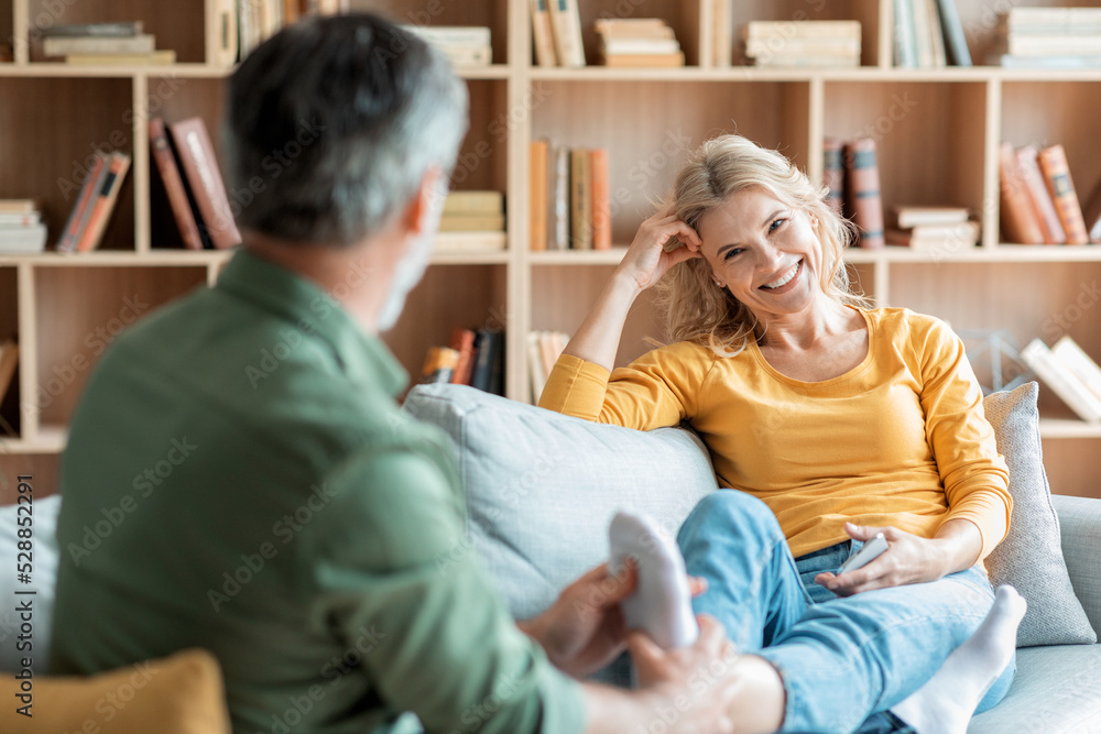 Caring Man Massaging Feet Of His Wife While They Relaxing On Couch Caring Man Massaging Feet Of His Wife While They Relaxing On Couch