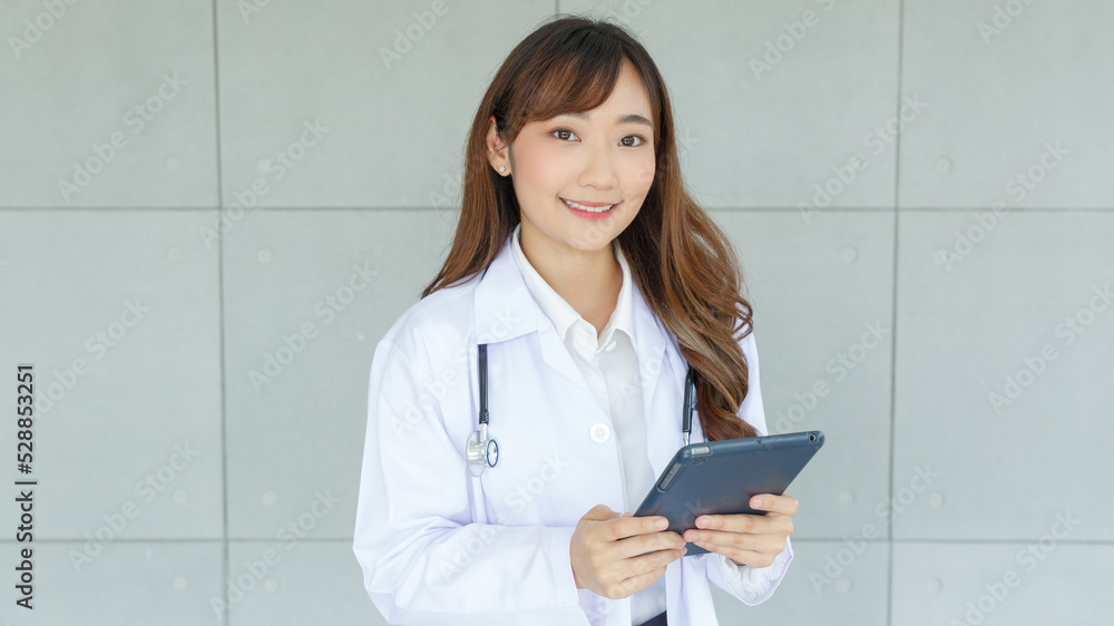 Beautiful and cheerful good mood young lady asian doctor dressed uniform smiling arm stethoscope while using tablet on lobby hospital background.. Beautiful and cheerful good mood young lady asian doctor dressed uniform smiling arm stethoscope while using tablet on lobby hospital background..