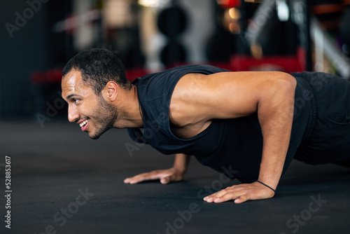 Muscular Young African American Man Doing Floor Push Up Exercise In Gym