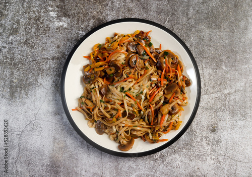 Vegetarian Lo Mein Noodles on a round plate on a dark background. Top view, flat lay