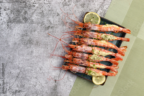 Сheese stuffed Argentinian red prawns with garlic and herbs on a rectangular plate on a dark background. Top view, flat lay