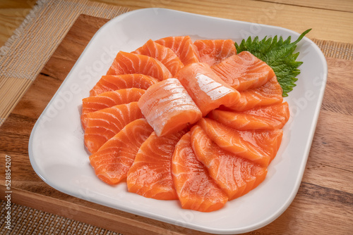 Sliced ​​Fresh Salmon white plate on wooden background, Salmon sashimi salmon sashimi with sauce and wasabi reday to eat.