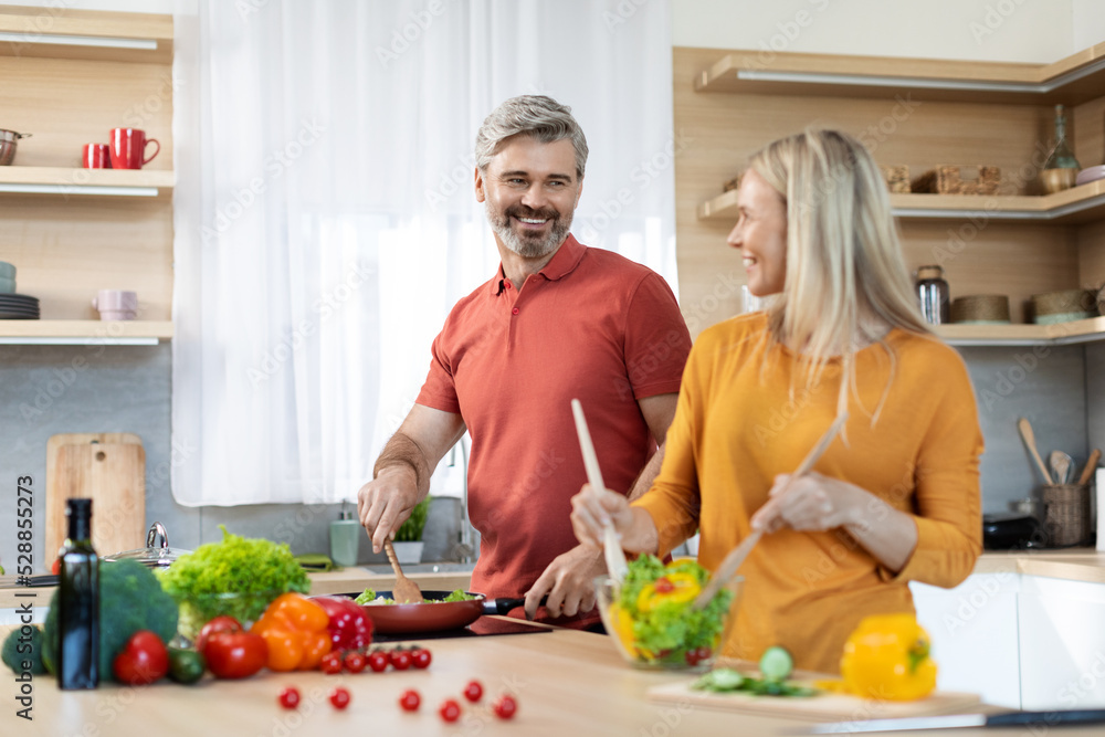 Loving spouses preparing healthy meal together, kitchen interior Loving spouses preparing healthy meal together, kitchen interior