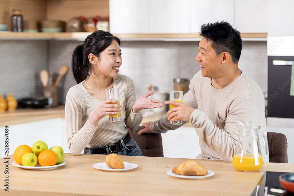 Happy asian spouses having fun while eating at kitchen Happy asian spouses having fun while eating at kitchen