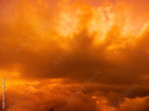 A red burning sunset over the sea with rocky volcanic cliff. Abstract nature summer or spring ocean sea background. Small waves on golden warm water surface with bokeh lights from sun.