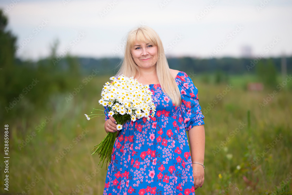 Beautiful plus size woman with white hair in a summer dress posing outdoors with daisies. Chubby girl in a meadow with flowers. Beautiful plus size woman with white hair in a summer dress posing outdoors with daisies. Chubby girl in a meadow with flowers.