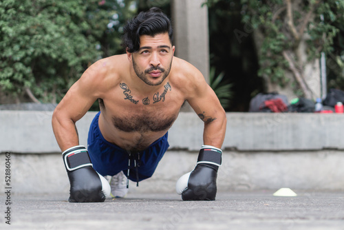 Handsome young Latino man with beard training without shirt in a park.