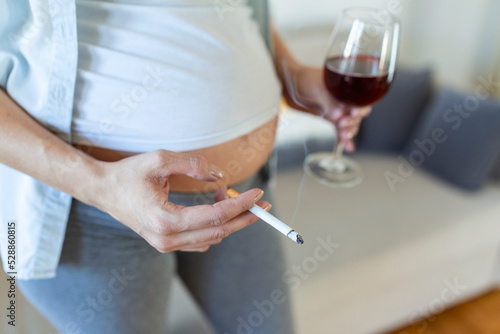 Smoking and alcohol pregnancy.woman on a long pregnancy drinking alcohol and Smoking cigarettes.problems of alcoholism and the period of bearing a child.danger of losing a baby, miscarriage. alcoholic © Graphicroyalty