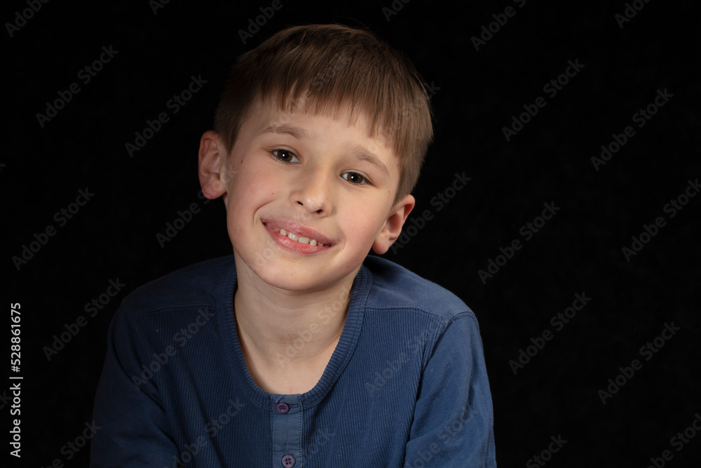 Portrait of a ten-year-old boy on a dark background. The child looks into the camera with intelligent eyes. Handsome boy of school age. Portrait of a ten-year-old boy on a dark background. The child looks into the camera with intelligent eyes. Handsome boy of school age.