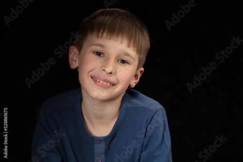 Portrait of a ten-year-old boy on a dark background. The child looks into the camera with intelligent eyes. Handsome boy of school age. photo