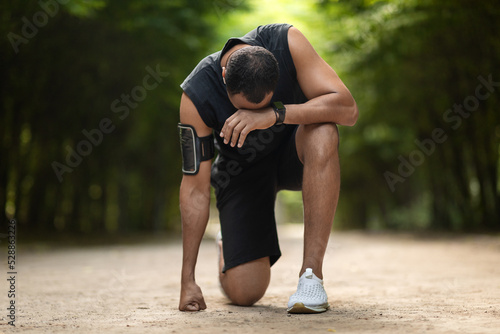 Black sportsman feeling bad while jogging by park