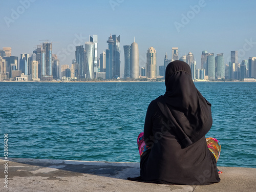A Muslim women with abaya dress facing to Doha skyline