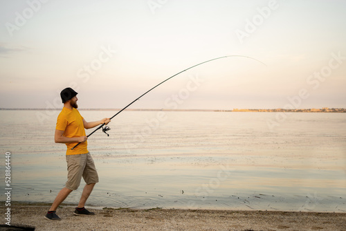Young man fishing in a pond in a sunny day. fisherman outdoor leisure lifestyle.