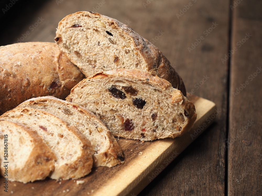 slice of whole wheat cereal and raisin bread on wooden board slice of whole wheat cereal and raisin bread on wooden board