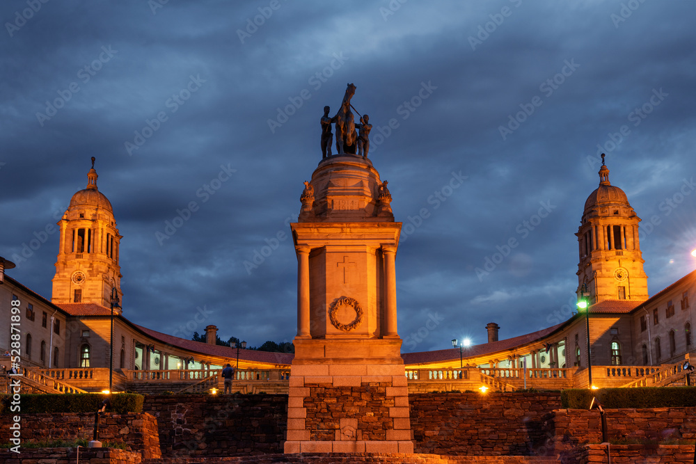 Obraz premium Evening shot of the Delville Wood memorial against a cloudy sky with the Union Buildings in the background, Pretoria, South Africa