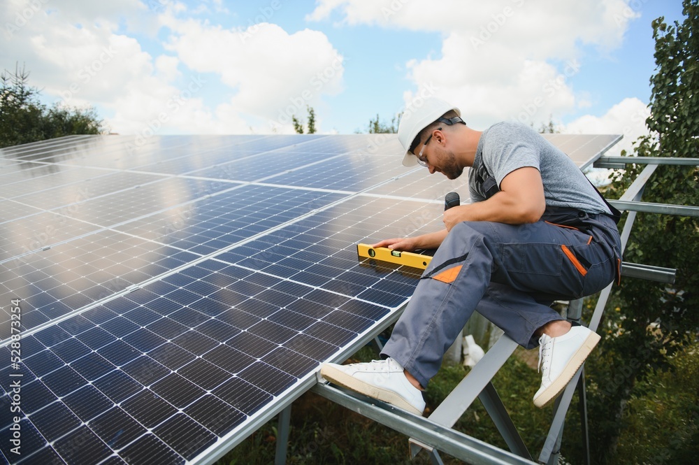 Male engineer in protective helmet installing solar photovoltaic panel system. Alternative energy ecological concept. Male engineer in protective helmet installing solar photovoltaic panel system. Alternative energy ecological concept.