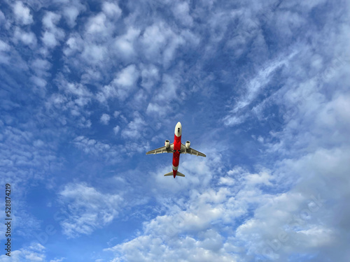 Beautiful airplane in the sky. Red white plane flies in the skies. Blue heaven and white clouds. Travel by plane. Aviation service. Amazing photo. Airplane at altitude in flight, view from the ground.