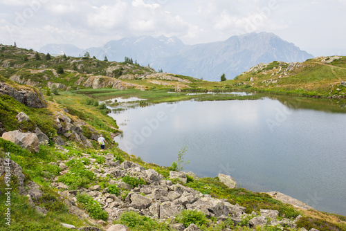 un lac de montagne dans les Alpes. Un homme se promène dans les bois.