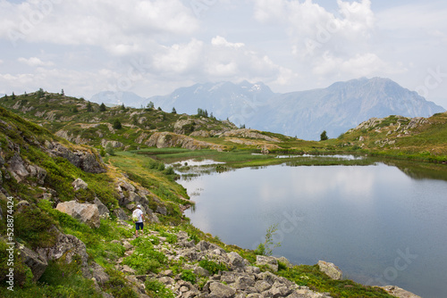 Fototapeta Naklejka Na Ścianę i Meble -  un lac de montagne dans les Alpes. Un homme se promène dans les bois.