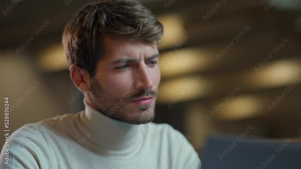 Handheld, portrait of a young designer working on a laptop, smiling man working in a cafe, the thinking process. Handheld, portrait of a young designer working on a laptop, smiling man working in a cafe, the thinking process.