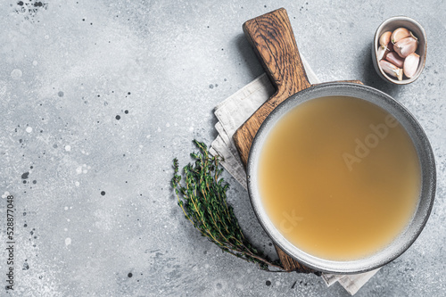 Bone meat chicken broth in a plate. Gray background. Top view. Copy space photo