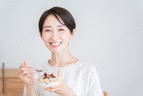 グラノーラを食べるミドル女性（朝食・食事・健康）