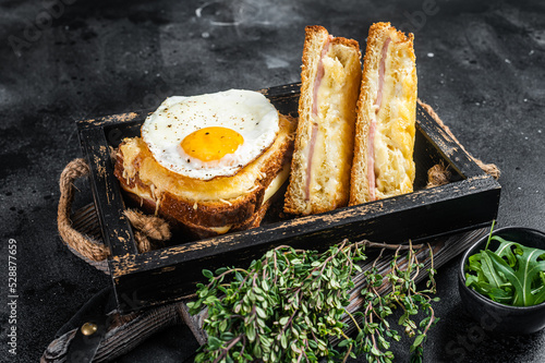 French toasts croque monsieur and croque madame with sliced ham, melted emmental cheese and egg. Black background. Top view photo