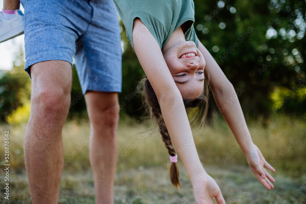 Father swing her daughter, holding her upside down, having fun together in nature. Father swing her daughter, holding her upside down, having fun together in nature.
