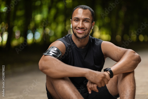 Positive black guy sportsman having break while training outdoors